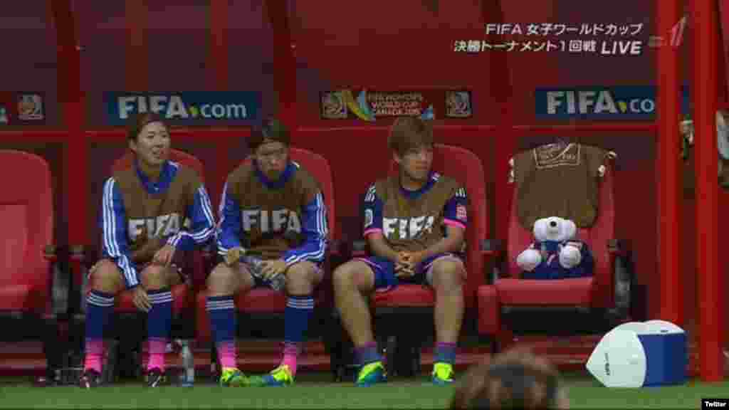 Jogadoras japonesas e um ursinho de peluche observam o jogo contra a Inglaterra na semi-final do Mundial Feminino da Fifa 2015.