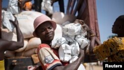 FILE - A man carries packages of food aid delivered by the U.N. Office for the Coordination of Humanitarian Affairs and World Food Program in Makunzi Wali, Central African Republic, April 27, 2017.