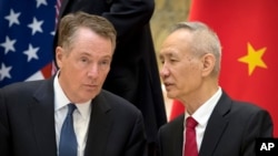 FILE - Chinese Vice Premier Liu He, right, talks with U.S. Trade Representative Robert Lighthizer, while they line up for a group photo in Beijing, Feb. 15, 2019.. 