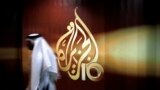 ARCHIVO: Un empleado de la cadena de televisión qatarí Al Jazeera camina frente al logo del canal en Doha, Qatar.