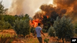 A man walks toward wildfires in Kacarlar village near the Mediterranean coastal town of Manavgat, Antalya, Turkey, July 31, 2021. The death toll from wildfires raging in Turkey's Mediterranean towns rose to six Saturday.