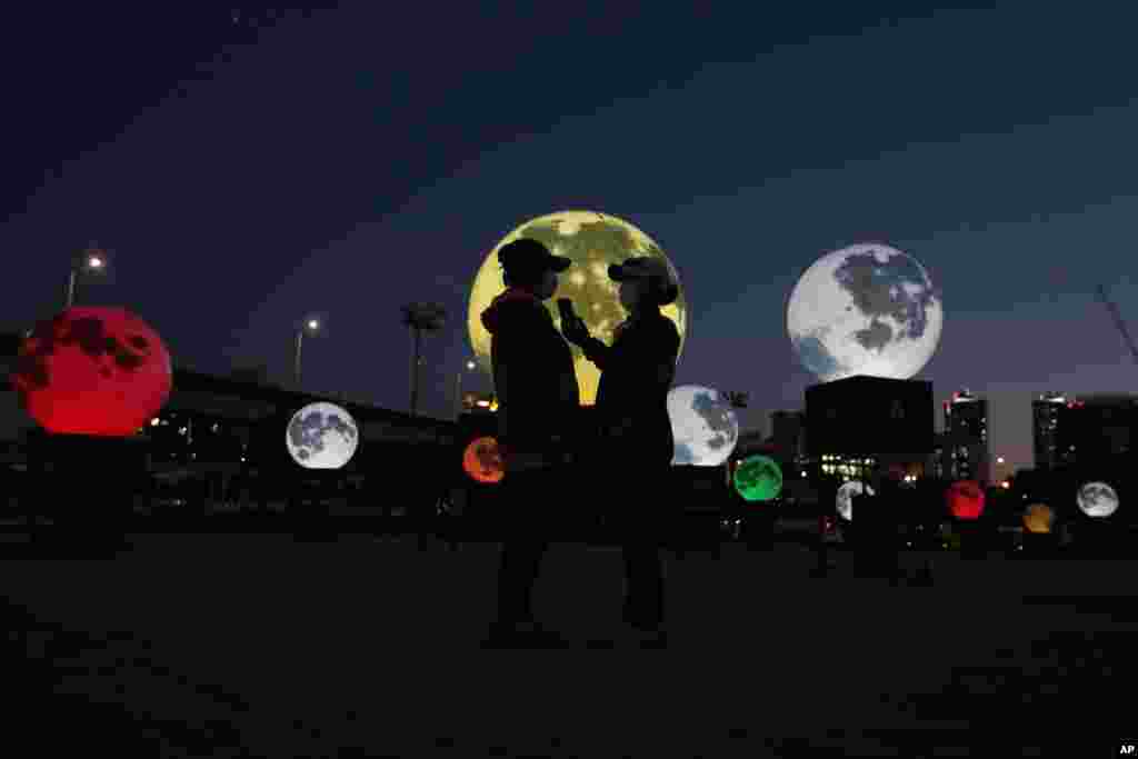 People stand next to glowing full moon installations at a park in Seoul, South Korea. The artificial full moons were installed to increase morale during COVID-19 and to celebrate the upcoming Chuseok holiday, the Korean version of Thanksgiving Day. 