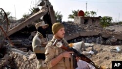 FILE - Iraqi soldiers advance their position in northern Ramadi, 115 kilometers (70 miles) west of Baghdad, Iraq, Dec. 21, 2015.