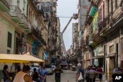 Passersby watch as residents are rescued by firemen in a basket crane from a building in which the interior staircase collapsed leaving dozens trapped, in Havana, Cuba, April 19, 2017.