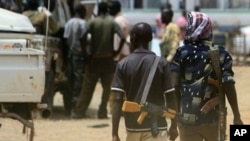 Armed men walk past on April 17, 2011 as resentment towards the capital Khartoum runs high in the restive town of Abyei, on the Sudanese north-south border, which suffers from chronic underdevelopment despite its strategic importance and the area's rich n