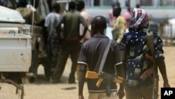 Armed men walk past as resentment towards the capital Khartoum runs high in the restive town of Abyei, on the Sudanese north-south border, which suffers from chronic underdevelopment despite its strategic importance and the area's rich natural resources (