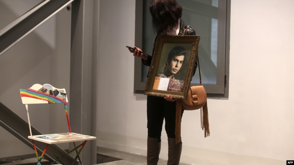 Nibal holds a portrait of her brother Ghaleb, a Lebanese man who went missing during the Lebanese civil war, as she stands next to an empty chair during an exhibit in Beirut, April 13, 2017.