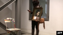 Nibal holds a portrait of her brother Ghaleb, a Lebanese man who went missing during the Lebanese civil war, as she stands next to an empty chair during an exhibit in Beirut, April 13, 2017.