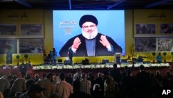 Hezbollah leader Sayyed Hassan Nasrallah delivers a broadcast speech through a giant screen, during a rally marking the12th anniversary of the 2006 Israel-Hezbollah war, in Beirut, Lebanon, Aug. 14, 2018.