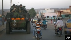 A motorcyclist waves his support as French troops in two armored personnel carriers drive through Mali's capital Bamako on the road to Mopti, January 15, 2013. 