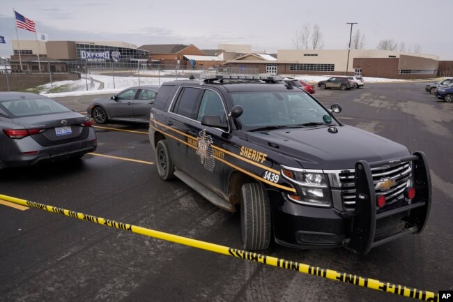 An Oakland County Sheriff's deputy guards the parking lot of Oxford High School in Oxford, Mich., Wednesday, Dec. 1, 2021. A 15-year-old sophomore opened fire at the school, killing several students and wounding multiple other people, including a teacher.