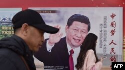 People walk past a poster of Chinese President Xi Jinping beside a street in Beijing on February 26, 2018. Xi Jinping's tightening grip on China had already earned the leader comparisons to Mao Zedong, but they came into even sharper focus after the party paved the way for him to assume the presidency indefinitely. (AFP PHOTO / GREG BAKER)