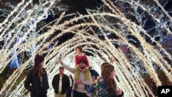 A family walks through a light display at the Lights of Joy display, Dec. 16, 2024, in Kennesaw, Ga.