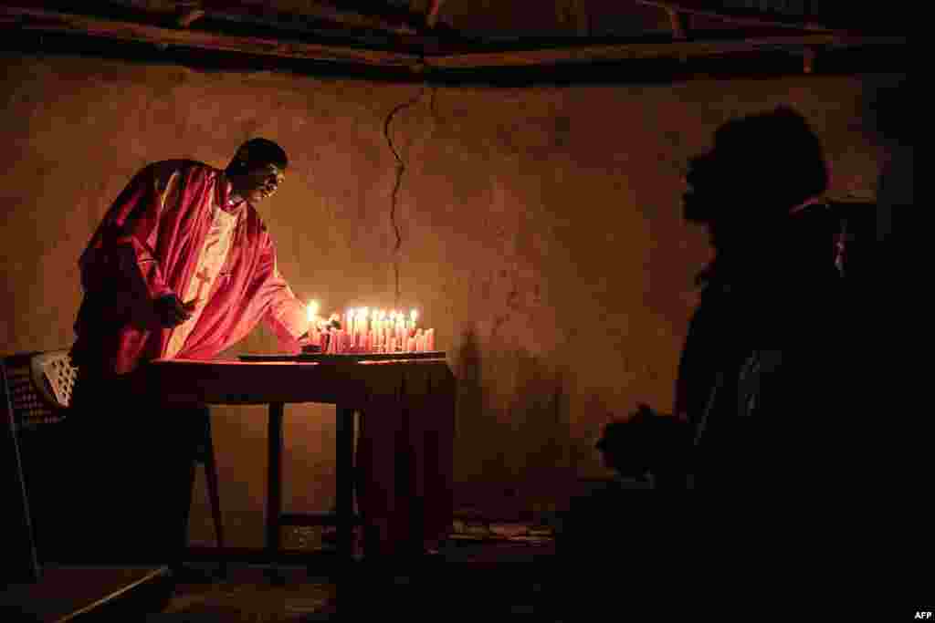 A priest of the Legio Maria African Church Mission lights candles during the Christmas Eve vigil mass in a church near Ugunja, on December 24, 2023.