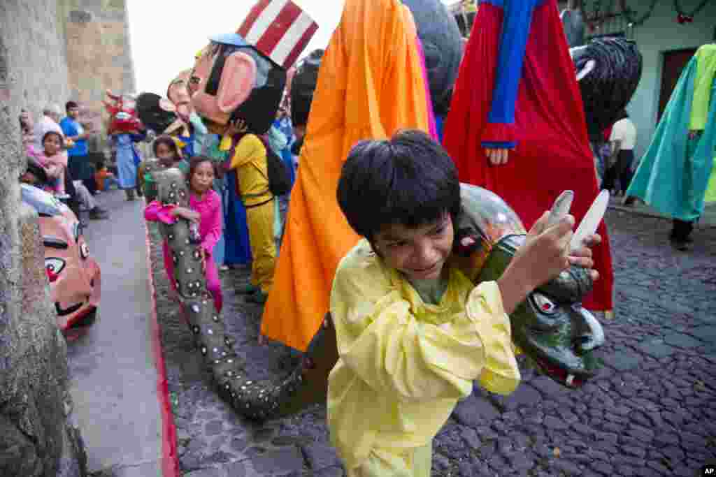 Children carry a snake made out of rags and paper mache as they take part in the traditional dance of "Los Gigantes," or "The Giants," during Christmas celebrations on Christmas Eve in Antigua Guatemala, Wednesday, Dec. 24, 2014. (AP Photo/Moises Castillo