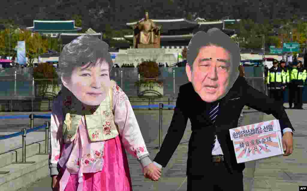 Protesters wearing masks depicting South Korean President Park Geun-Hye (L) and Japanese Prime Minister Shinzo Abe (R) hold hands during an anti-Japanese rally in Seoul. The protesters oppose Abe's upcoming trip to Seoul for a summit with Park.