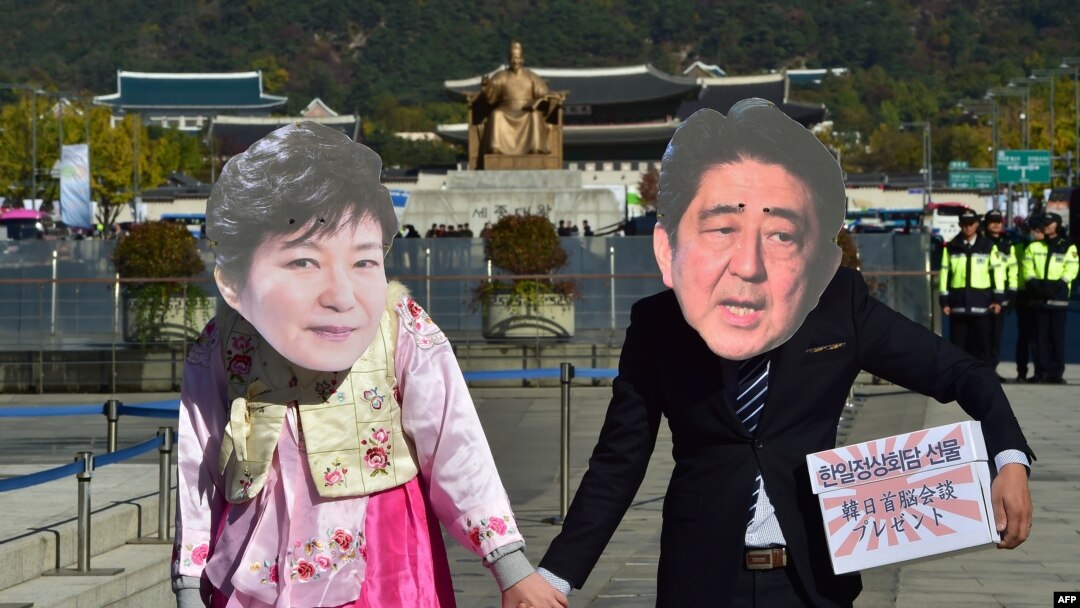 FILE - Protesters wearing masks depicting South Korean President Park Geun-Hye (L) and Japanese Prime Minister Shinzo Abe (R) hold hands during an anti-Japanese rally in Seoul. South Korea President Park Geun-hye and Japanese Prime Minister Shinzo Abe promised to resolve the long-standing dispute over comfort women by year’s end.