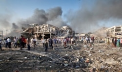 FILE - Somalis gather and search for survivors near destroyed buildings at the scene of a blast in the capital Mogadishu, Somalia, Oct. 14, 2017.