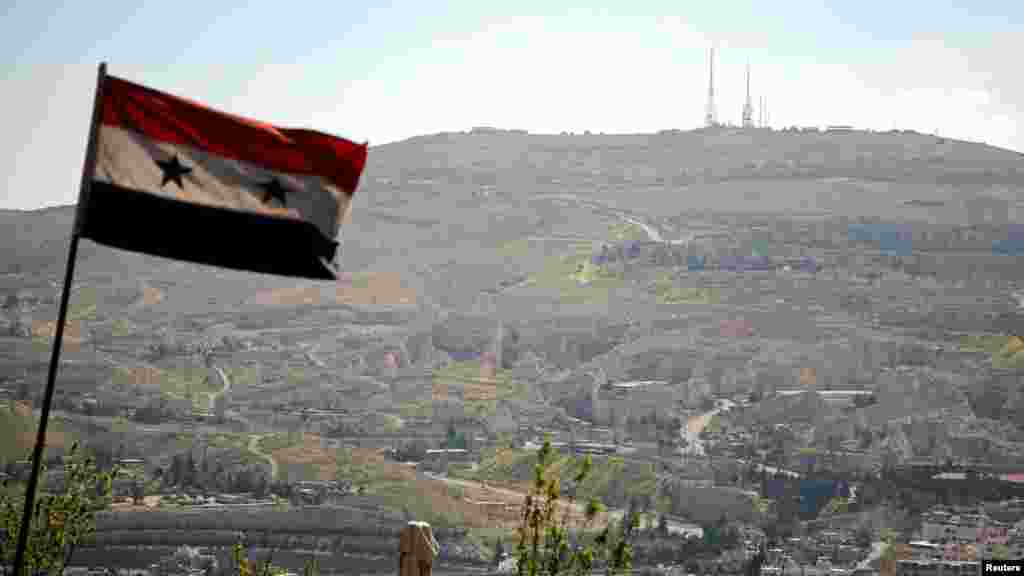 A Syrian national flag flutters as Qasioun mountain is seen in the background from Damascus, Syria, April 7, 2017. 