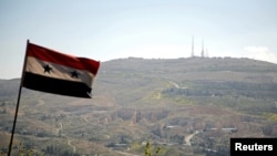 Una bandera nacional siria ondea, al fondo la montaña de Qasioun en Damasco, Siria, 7 de abril de 2017.