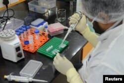 FILE - A research scientist works inside a laboratory of India's Serum Institute, the world's largest maker of vaccines, which is working on vaccines against COVID-19 in Pune, India, May 18, 2020.