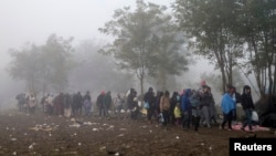 FILE - Migrants walk through a field trying to cross the border with Croatia near the village of Berkasovo, Serbia October 23, 2015. 