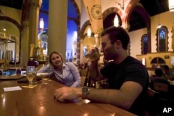 FILE - Jesse Hulien, right, drinks a beer as Molly Hartman, left, looks on, at the Church Brew Works, a former church renovated into a brewery, in Pittsburgh, Aug. 7, 2017.