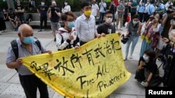 Aktivis pro-demokrasi Figo Chan, Avery Ng dan lainnya memegang spanduk di depan media sebelum persidangan atas dakwaan terkait sidang tidak sah pada 1 Oktober 2019, di luar pengadilan di Hong Kong, China, 17 Mei 2021. (Foto : REUTERS/Lam Yik)