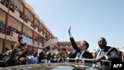 Le président français Emmanuel Macron (2ème à driote) et le président sénégalais Macky Sall (à droite) saluent la foule et les étudiants lors d'une visite inaugurale de l'école secondaire Bel-Air à Dakar, le 2 février 2018.