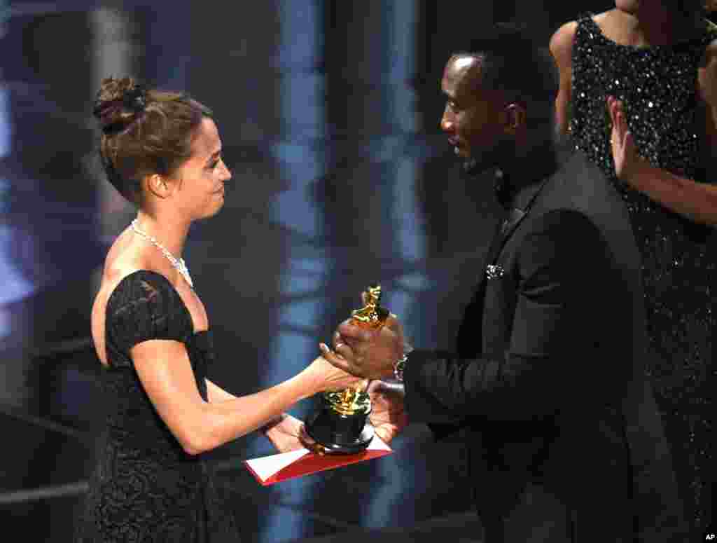 Mahershala Ali (kanan) dari film &quot;Moonlight&quot; menerima piala aktor pendukung terbaik Oscar 2017 dari aktris&nbsp;Alicia Vikander, dalam cara di Dolby Theatre (26/2) di Los Angeles.&nbsp;