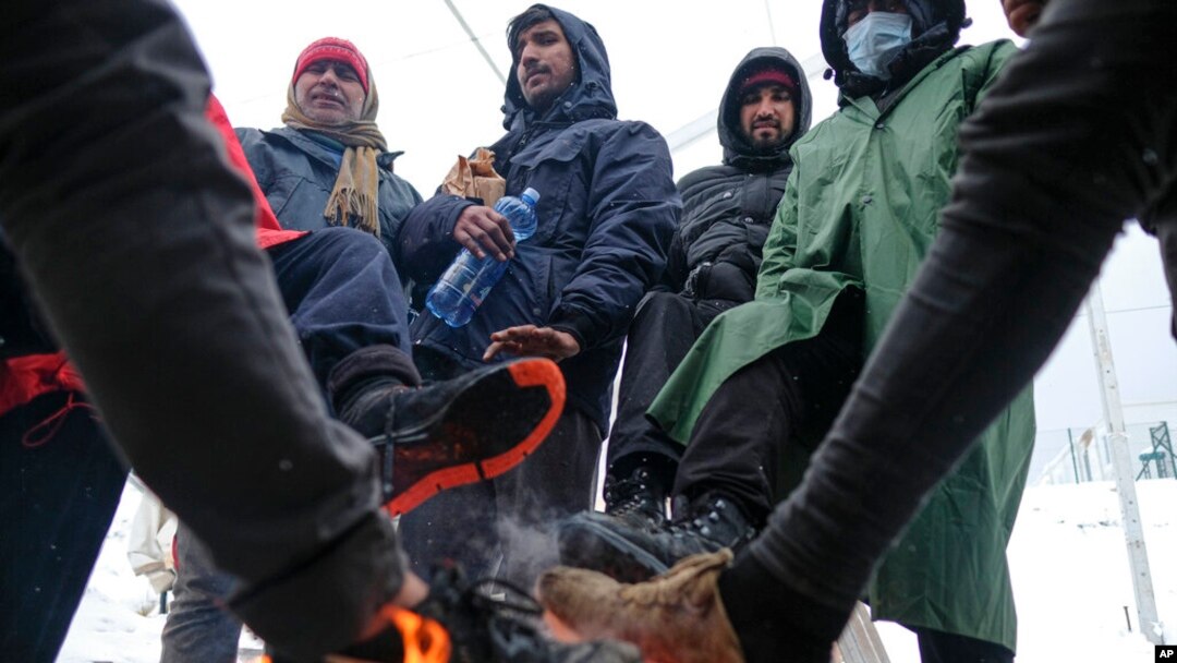 Para migran menghangatkan kaki dekat api unggun di kamp Lipa, barat daya Bosnia, dekat perbatasan dengan Kroasia, Sabtu, 26 Desember 2020. 