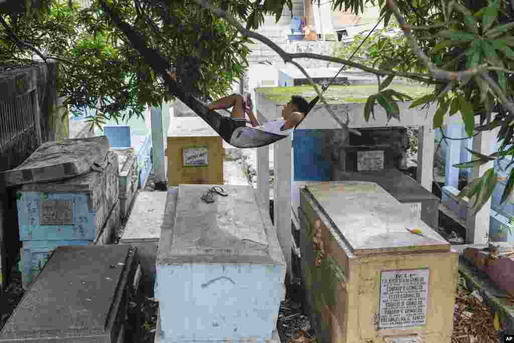 A man who lives inside the North Cemetery relaxes on his hammock on top of tombs in Manila, Philippines.