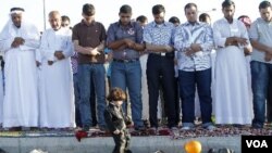 Seorang anak kecil bermain dengan balon di depan para pria Suriah yang sedang sholat Idul Fitri berjamaah di luar Kedutaan Suriah di Amman, Yordania, Selasa (30/8).