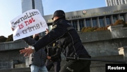 FILE - Police officers restrain a protester during a rally of journalists against a new media bill, in front of the Parliament building in Baku, Azerbaijan, on Dec. 28, 2021. 