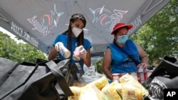 Volunteers load food into bags at a food and mask distribution site put on by the Miami Marlins baseball organization, June 29, 2020, outside Marlins Park stadium in Miami. 