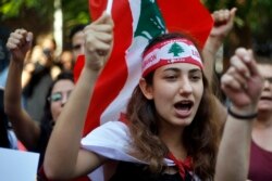 FILE - Protesters chant slogans during protests against the Lebanese government, in front of the central bank, in Beirut, Oct. 28, 2019.