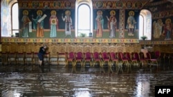 A woman cleans the floor of a church after the flood water withdrew from the village of Pechea, Romania, on Sept. 15, 2024.