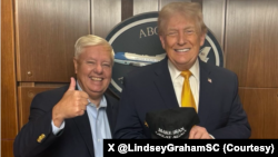 سناتور جمهوری‌خواه آمریکایی، لیندزی گراهام در کنار دونالد ترامپ، رئیس جمهوری آمریکا که کلاه «ایران را دوباره با عظمت کن» را در دست دارد.