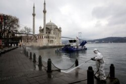 FILE - A worker sprays disinfectant outside Ortakoy Mosque to prevent the spread of coronavirus disease in Istanbul, Turkey, March 23, 2020.