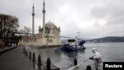 A worker sprays disinfectant outside Ortakoy Mosque to prevent the spread of coronavirus disease in Istanbul, Turkey, March 23, 2020. 