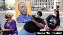 Jerlano Bell dari North Carolina menunjukkan poster George Floyd dalam pawai yang digelar oleh George Floyd Memorial Foundation untuk memperingati satu tahun kematiannya, di luar Pusat Pemerintah Hennepin County di Minneapolis, Minnesota, 23 Mei 2021. (Fo