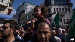 Palestinska devojčica sa plastičnom puškom na očevima ramenima tokom protesta u Ramali na Zapadnoj obali (Foto: AP/Nasser Nasser)