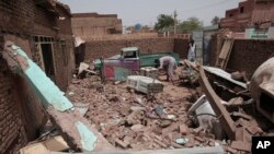FILE: A man cleans debris of a house hit in recent fighting in Khartoum, Sudan, Tuesday, April 25, 2023. Sudan's warring generals have pledged to observe a new three-day truce, which is largely holding despite breakouts of violence. 