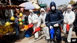 Workers wearing protective gear spray disinfectant as a precaution against the coronavirus, at the main market in Gaza City, March 19, 2020. 