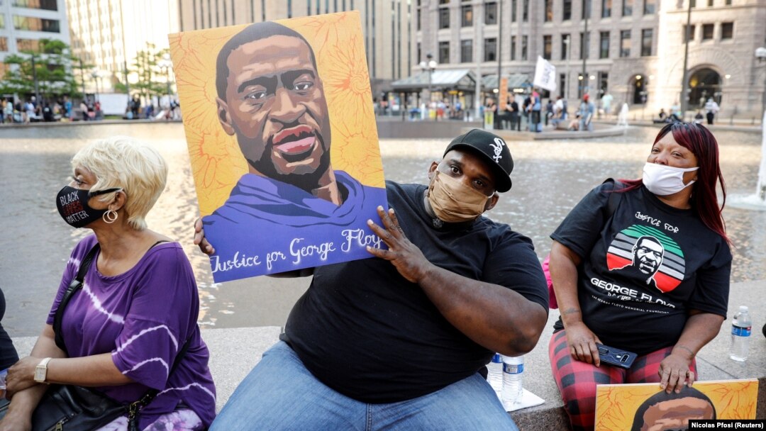 Jerlano Bell of North Carolina holds up a George Floyd sign at the "One Year, What's Changed?" rally hosted by the George Floyd Memorial Foundation to commemorate the first anniversary of his death, outside the Hennepin County Government Center