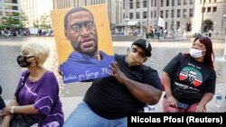 Jerlano Bell of North Carolina holds up a George Floyd sign at the "One Year, What's Changed?" rally hosted by the George Floyd Memorial Foundation to commemorate the first anniversary of his death, outside the Hennepin County Government Center