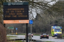 Vehicles drive past a roadside public health information sign, amidst the spread of the coronavirus pandemic, near Oxford, Britain, Dec. 28, 2020.