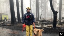 Eric Darling y su perro Wyatt son parte de un equipo del condado Orange, en el sur de California que ayuda a buscar restos en un parque de casas móviles en Paradise, California. Noviembre 23 de 2018.
