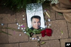 A rose lays next to an image of Muhammad Ali at a makeshift memorial at the Muhammad Ali Center, June 5, 2016, in Louisville, Ky. Ali, the heavyweight champion whose fast fists and irrepressible personality transcended sports and captivated the world, die