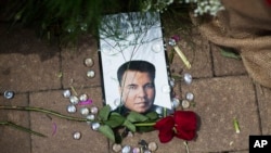 A rose lays next to an image of Muhammad Ali at a makeshift memorial at the Muhammad Ali Center, June 5, 2016, in Louisville, Ky. Ali, the heavyweight champion whose fast fists and irrepressible personality transcended sports and captivated the world, die